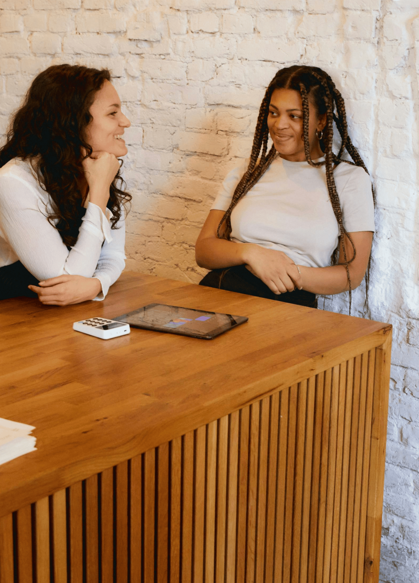 Two restaurant staff in conversation near a payment counter.