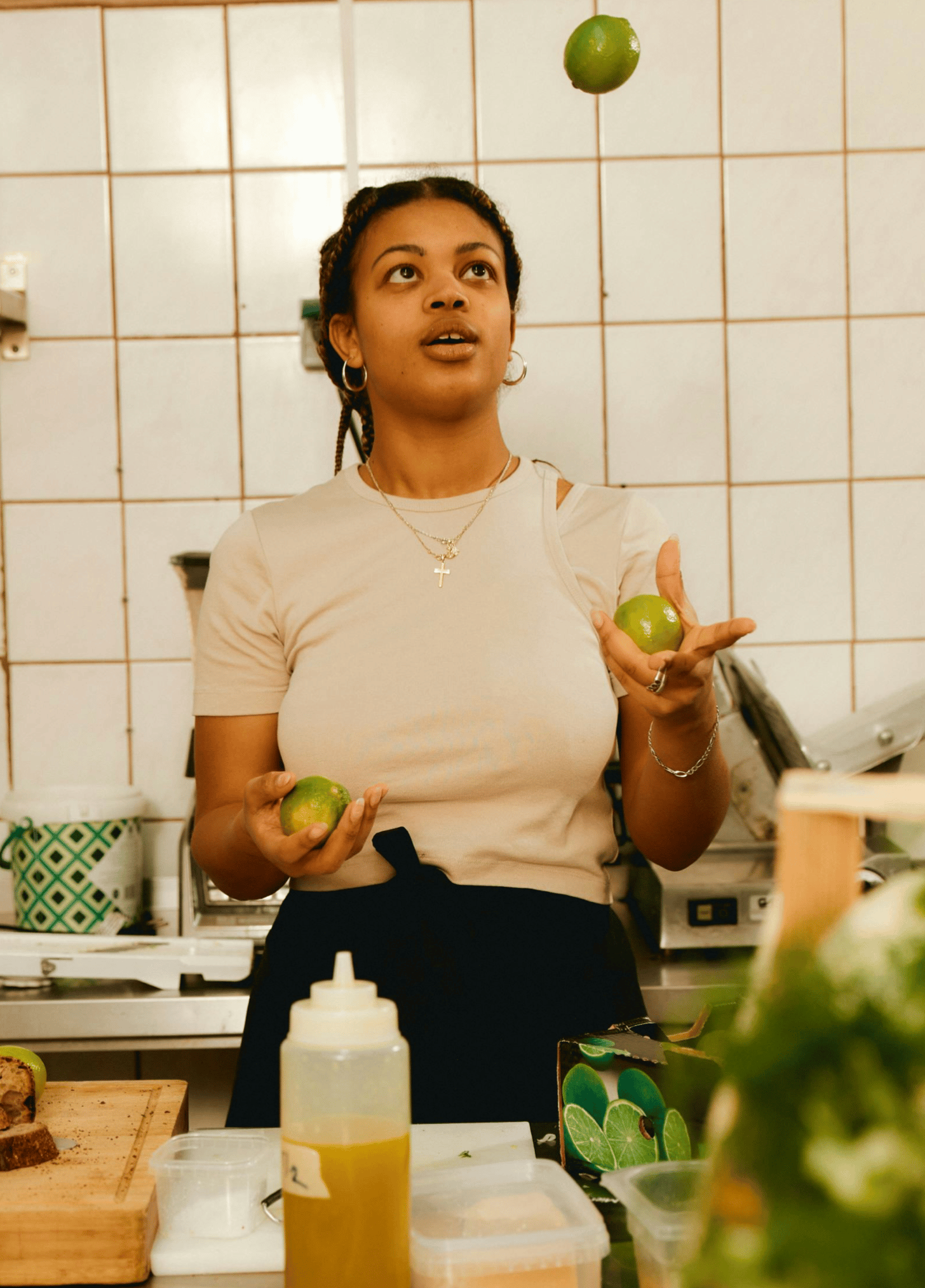 Restaurant staff member juggling limes in the kitchen.